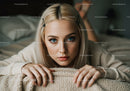 Young Woman with Blue Eyes and Blonde Hair Lying on Cozy Bed
