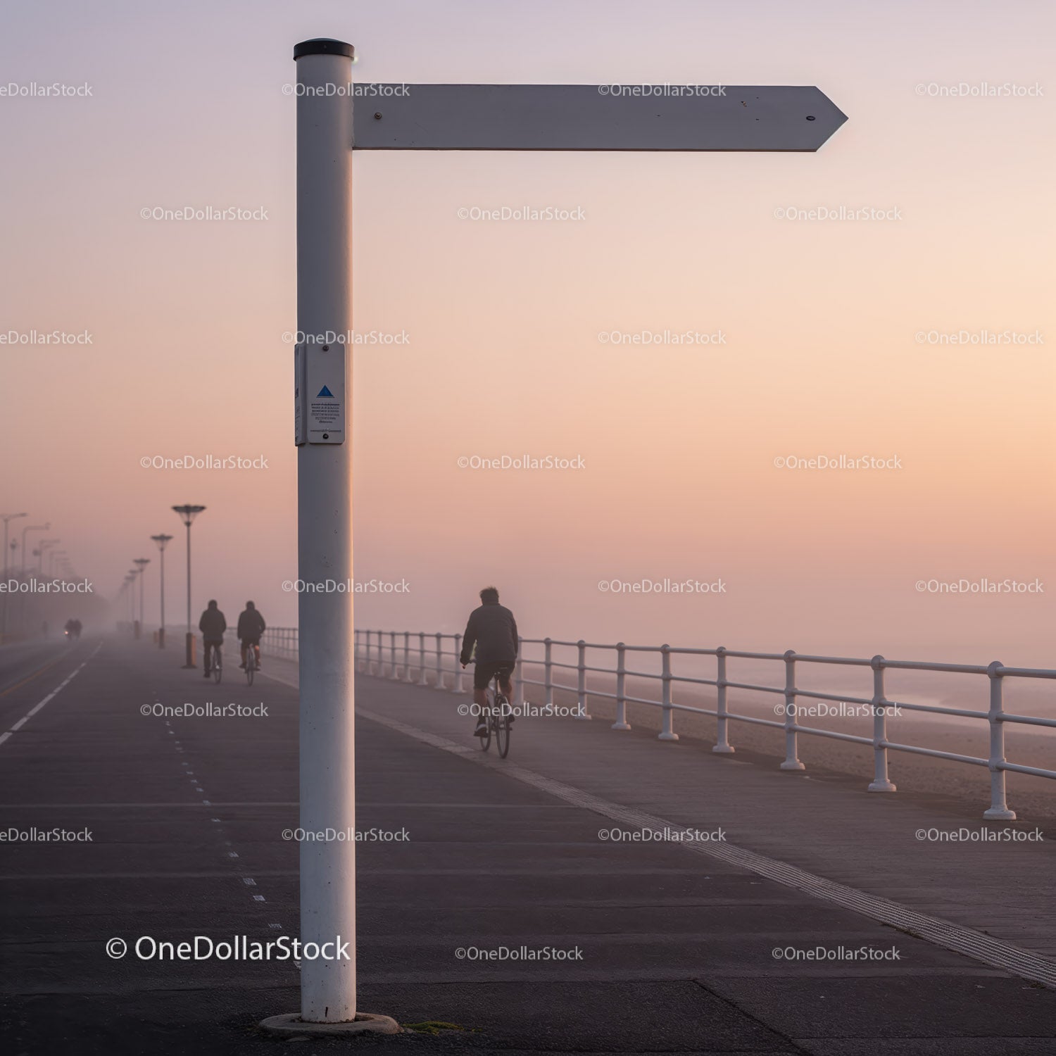Cyclists Riding Along Misty Seaside Promenade at Dawn