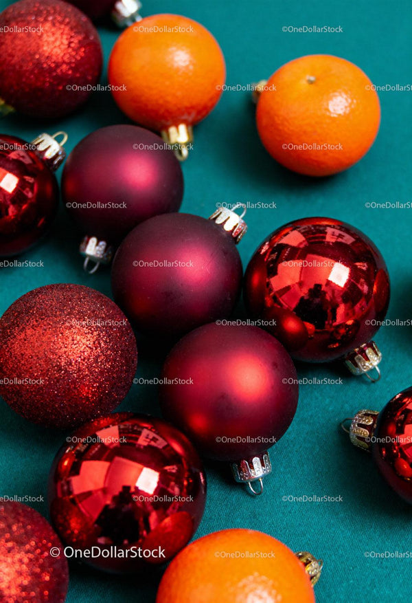 Festive red baubles and fresh oranges on teal fabric