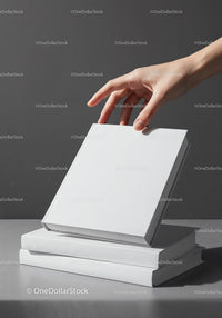 Hand picking a white book from stacked hardcover books