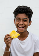 Joyful Boy Smiling Holding Pineapple Slice in Bright Outdoor Setting