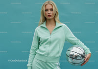 Young Woman in Mint Green Tracksuit Holding Disco Ball in Studio