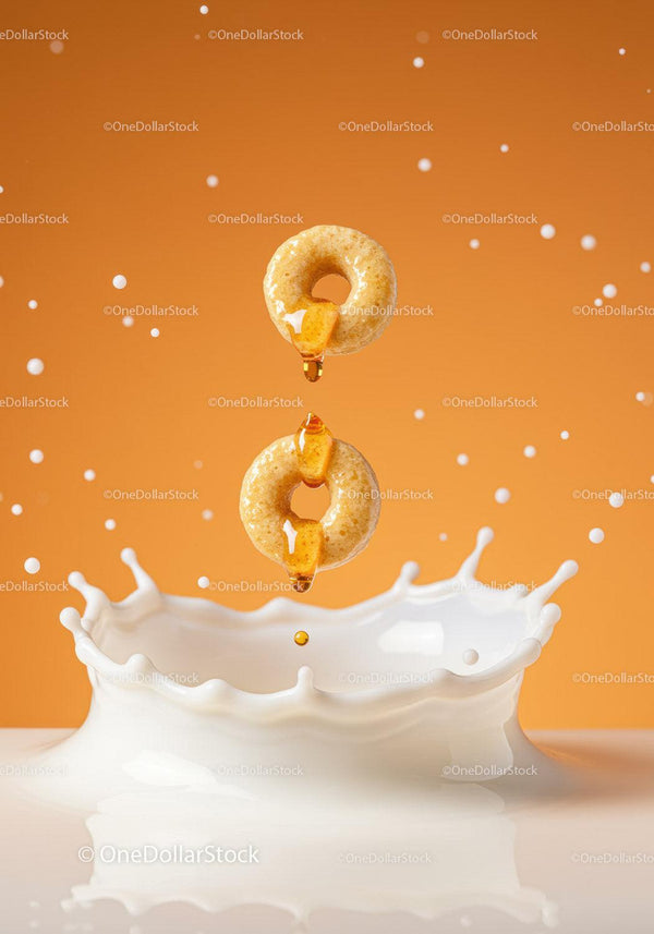Two Honey Drizzled Cereal Rings Splashing into Milk
