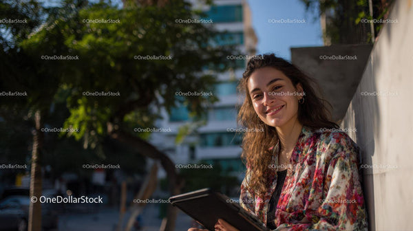 Young Woman Smiling with Tablet in an Urban Outdoors Setting