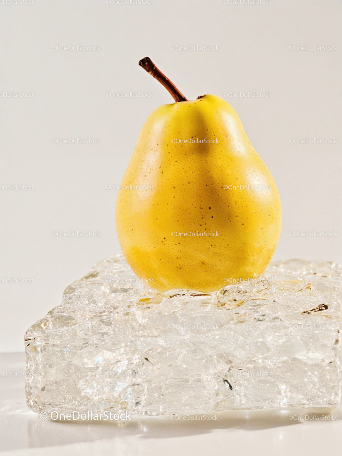 Fresh yellow pear resting on textured ice block