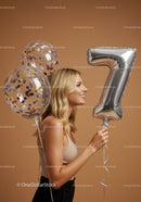 Smiling woman celebrating with number seven balloon