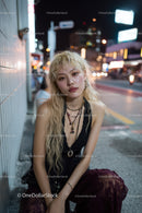 Fashionable Young Woman Sitting on City Sidewalk at Night