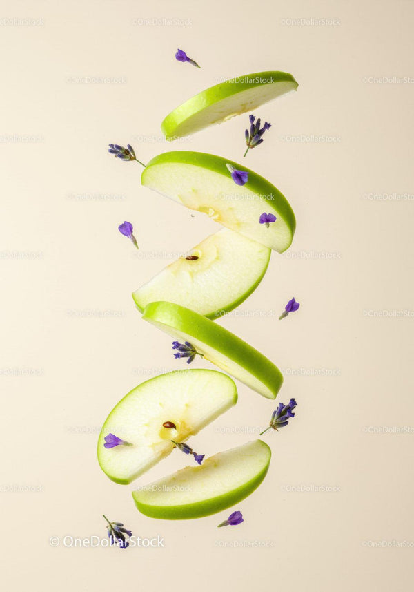 Fresh green apple slices with delicate purple flowers