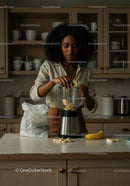 Young woman preparing banana smoothie in modern kitchen