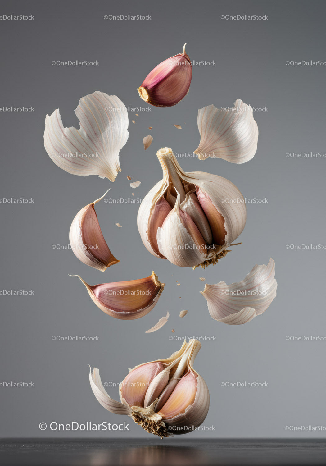 Floating garlic cloves and peels in mid air with gray background