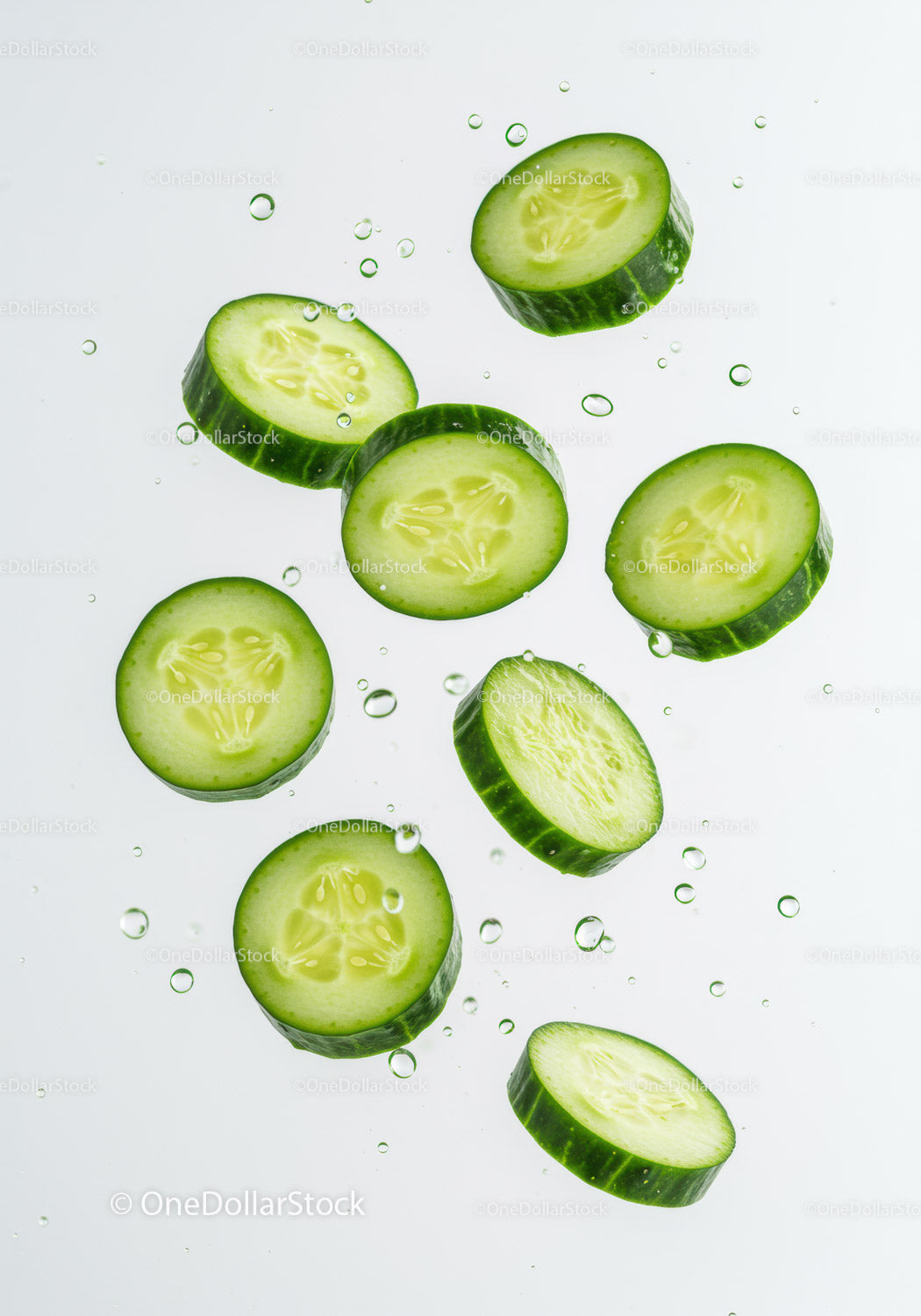 Fresh cucumber slices floating in clear water droplets