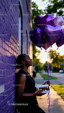 Young woman holding heart balloons and chocolates outdoors