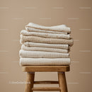 Stack of Soft Beige Textiles on Wooden Stool