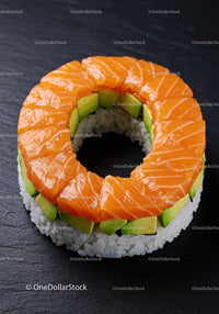 Ring-shaped sushi with salmon and avocado on black slate