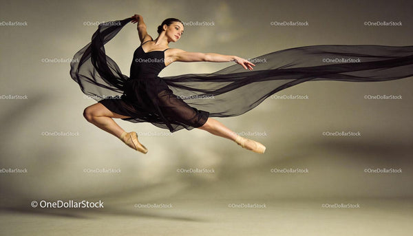 Graceful ballet dancer mid-air leap with flowing fabric