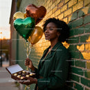 Woman holding heart balloons and chocolates outdoors