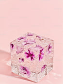 Clear cube with vibrant purple flowers on pastel pink