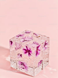 Clear cube with vibrant purple flowers on pastel pink