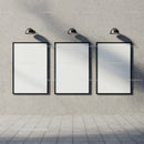Three blank frames on urban concrete wall under lights