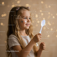 Smiling girl holding glowing spoon with magical sparkles
