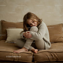 Cozy child hugging knees on soft textured sofa