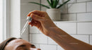 Woman Applying Skincare Serum with Dropper in Bathroom