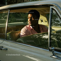 Young Man Sitting in Vintage Car Looking Out Window