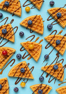 Waffle slices with berries and drizzled chocolate on blue
