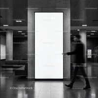 Man walking past large blank illuminated advertising panel