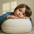 Thoughtful child resting head on soft white cushion