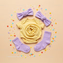 Bright baby clothes set with purple accessories flat lay