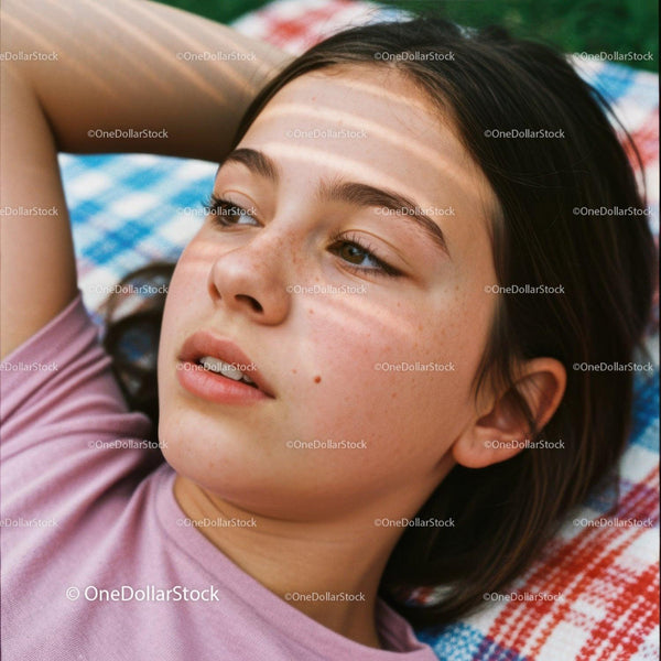 Thoughtful young girl resting on colorful blanket
