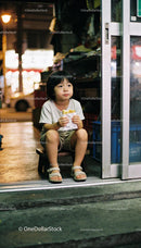 Young child enjoying a sandwich on street at night