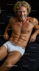 Relaxed muscular man in white underwear lying on bed