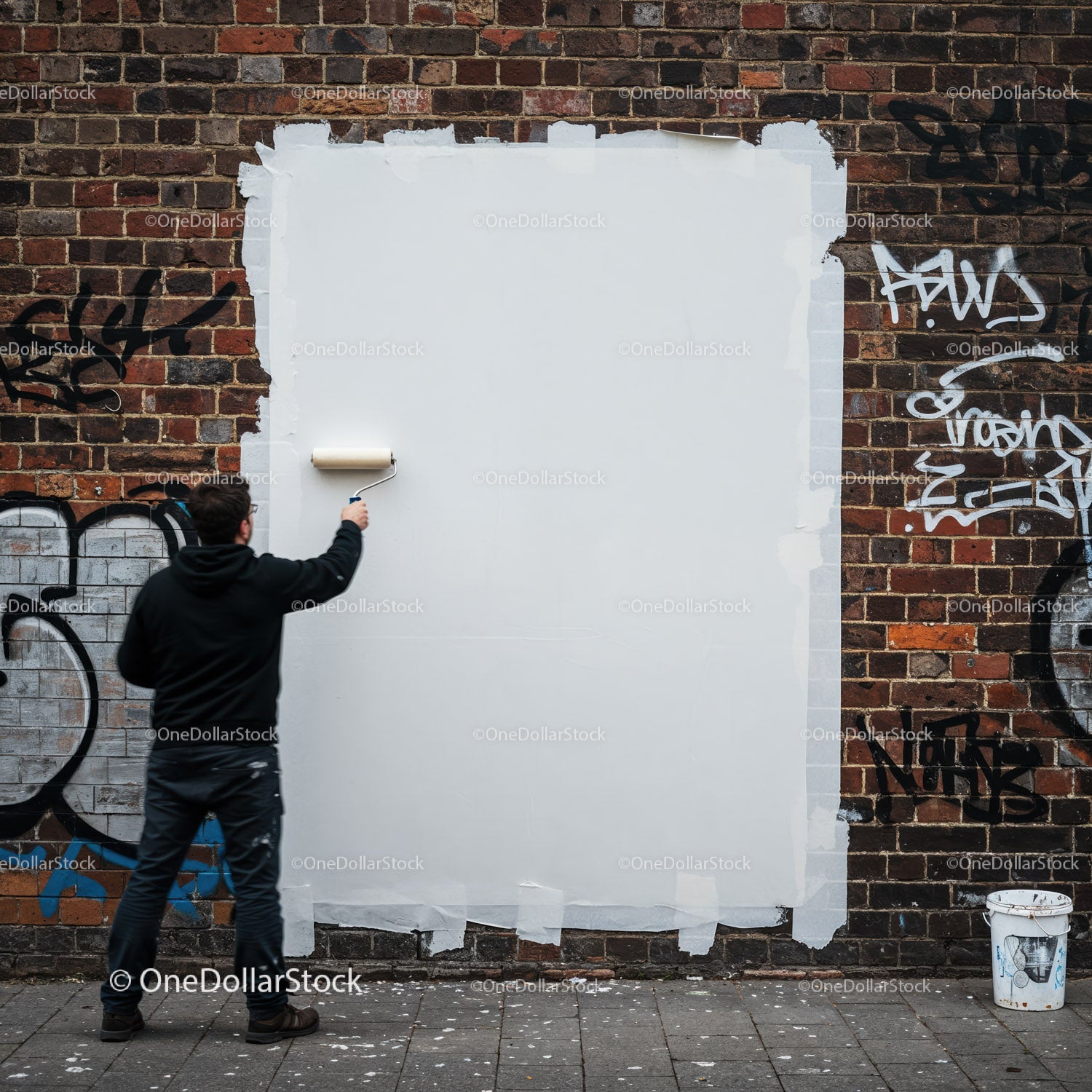 Mężczyzna malujący graffiti na miejskiej ścianie z cegły