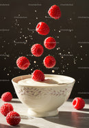 Fresh raspberries falling into creamy yogurt bowl