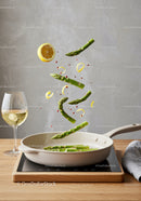Fresh asparagus and lemon slices sizzling in pan