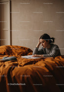 Contemplative Woman Reading Book on Bed in Cozy Bedroom