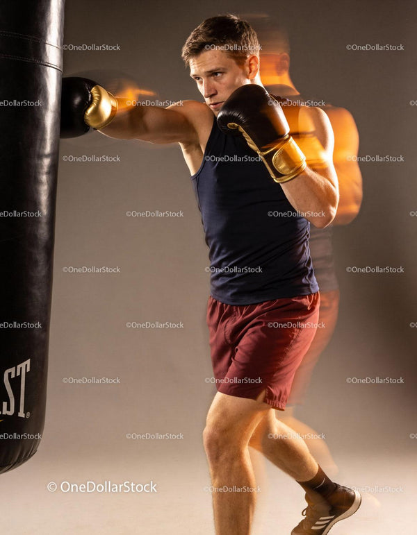 Focused boxer training with black punching bag in studio