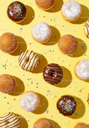 Assorted glazed donuts with sprinkles on vibrant yellow