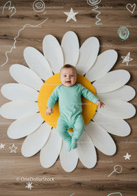 Happy baby lying on large decorative daisy flower