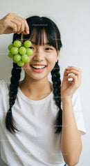 Smiling Young Woman Holding Green Grapes in Bright Indoor Setting