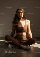 Young woman in brown activewear seated on floor indoors