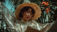 Woman Relaxing in Tropical Garden with Straw Hat and Book