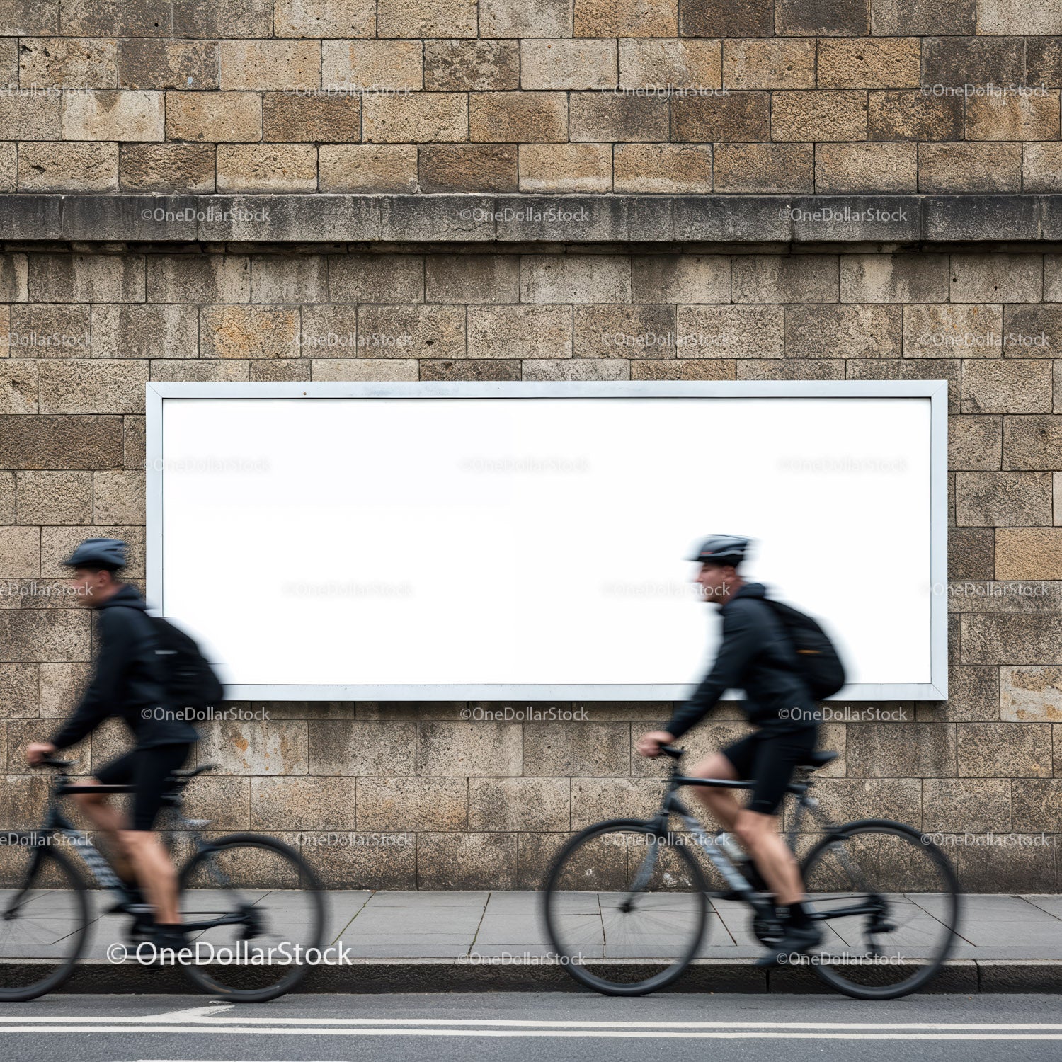 Rowerzyści mijają pusty billboard na miejskim murze kamiennym