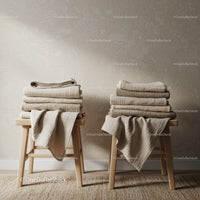 Folded neutral linens stacked on wooden stools indoors