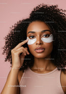 Young Woman with Curly Hair Showing Under Eye Patches for Skin Care