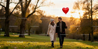 Couple walking in park holding heart shaped balloon