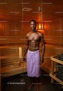 Young Muscular Man Standing in Sauna with Wooden Interior and Towel