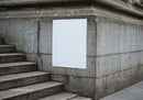 Blank white poster on urban stone wall near stairs
